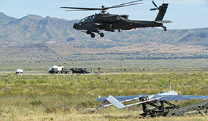 An Apache helicopter takes off at Dugway's Michael Army Airfield as the Shadow unmanned aircraft is readied for its flight onto the battlefield. - Credit: U.S. ARMY PHOTO BY KARI HAWKINS